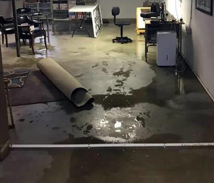 semi-finished basement showing pools of water and a rolled up area rug