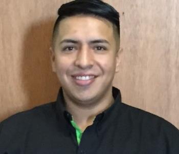 employee in a black logo SERVPRO jacket, posing