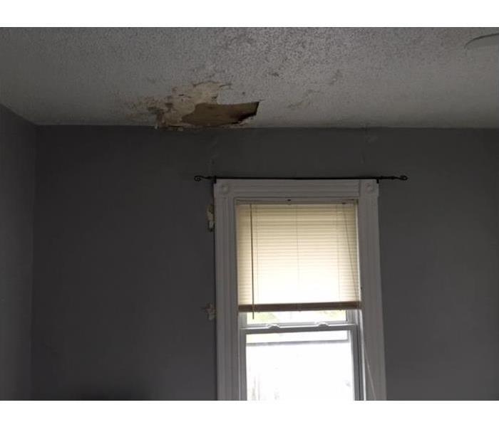 Ceiling and wall with water damage showing around a window