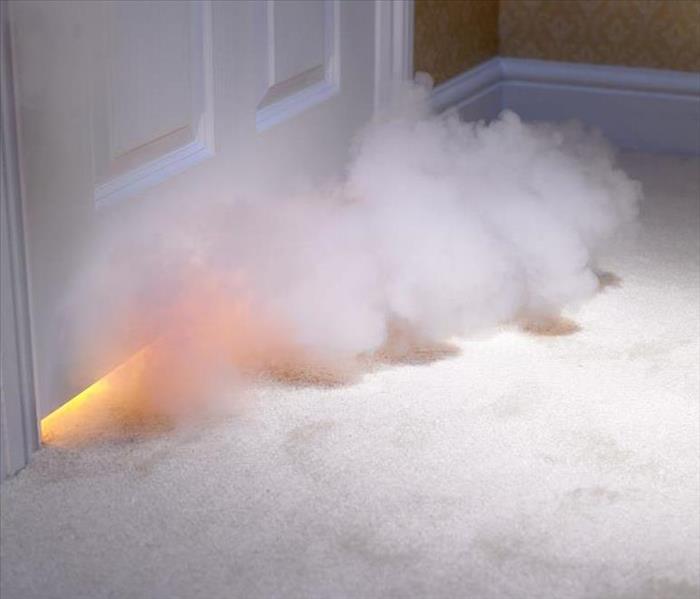 Smoke billowing out from under a door. 