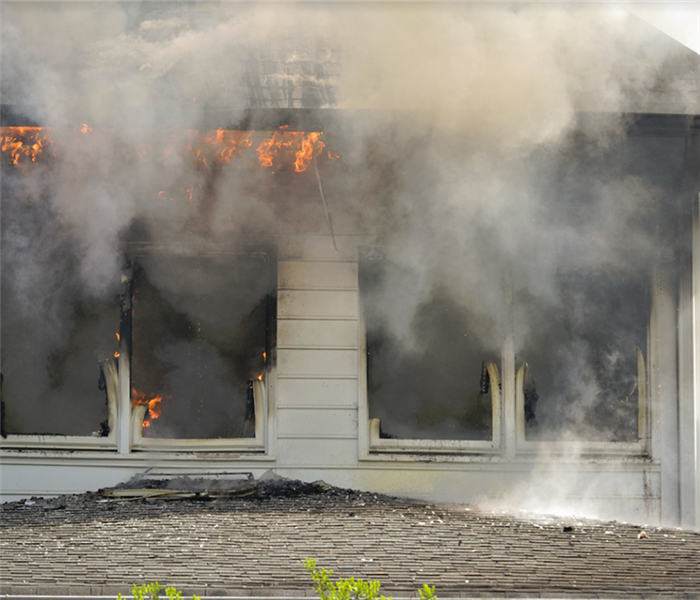 smoke billowing from the windows of a house with a fire inside