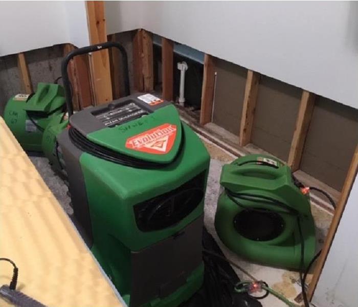 SERVPRO restoration equipment being used in water damaged room; flood cuts along wall